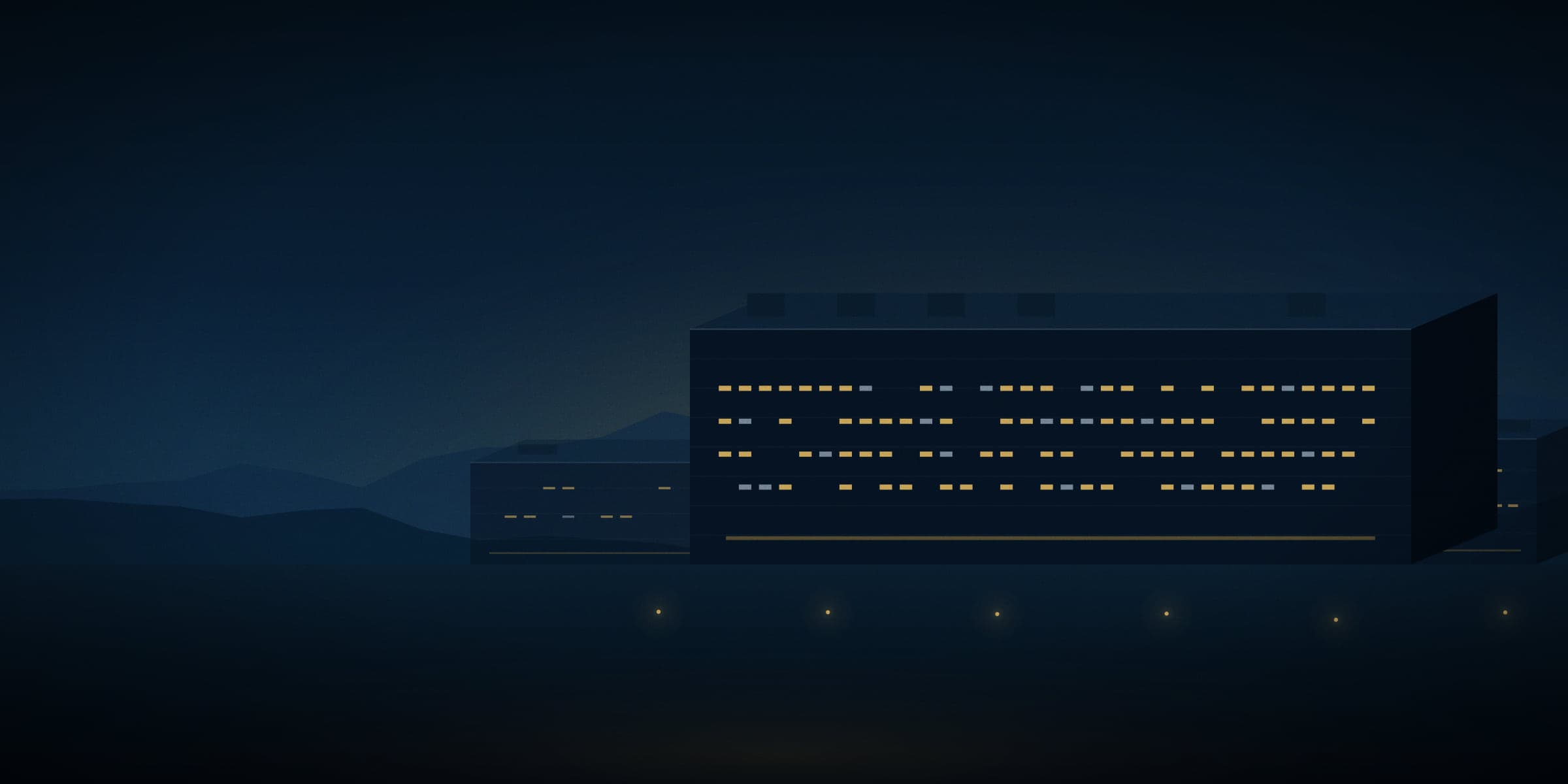 Data centre halls lit at dusk beneath a mountain ridge.